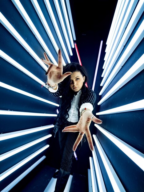 Ragazza della discoteca in interni futuristici. Colori bianco e blu. Lampade al neon orizzontali intorno alla ragazza che balla.