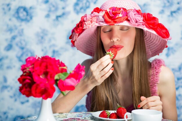 Ragazza della fragola Cappello da portare della signora elegante che mangia il dessert