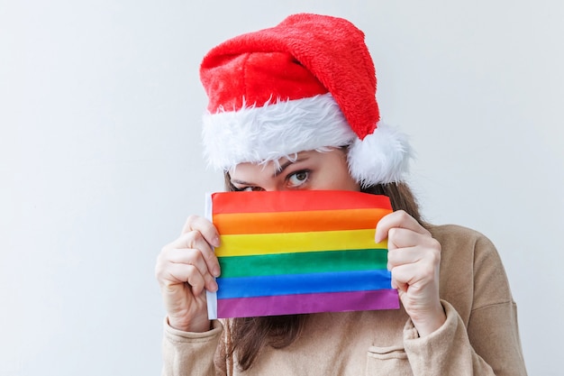 Ragazza della giovane donna in cappello rosso di Babbo Natale con bandiera arcobaleno LGBT