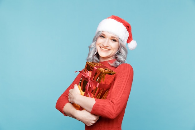 Ragazza della Santa che tiene il regalo dorato con il nastro rosso isolato