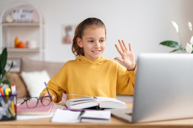 Ragazza della scuola che ha lezione online a casa tramite la webcam del laptop