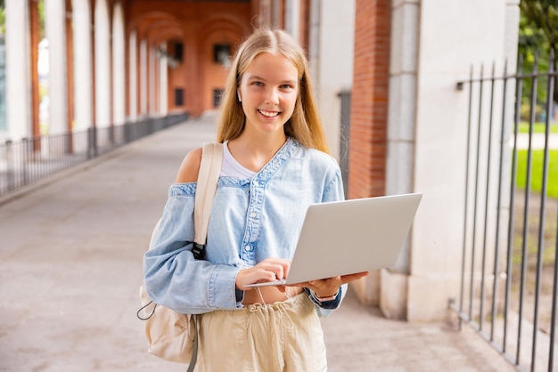 Ragazza della scuola che tiene il computer portatile