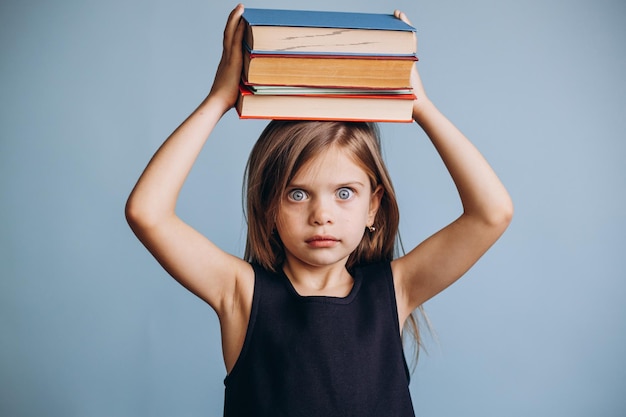 Ragazza della scuola che tiene libri sopra la sua testa