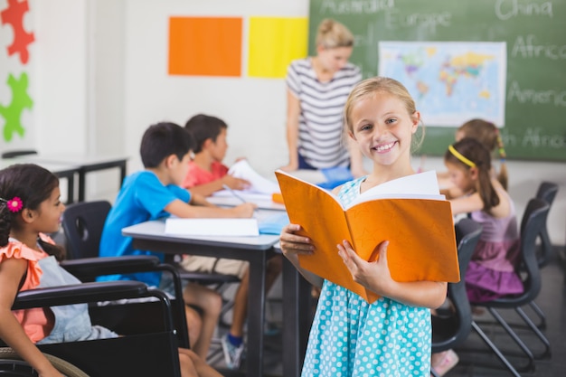 Ragazza della scuola che tiene un libro in aula