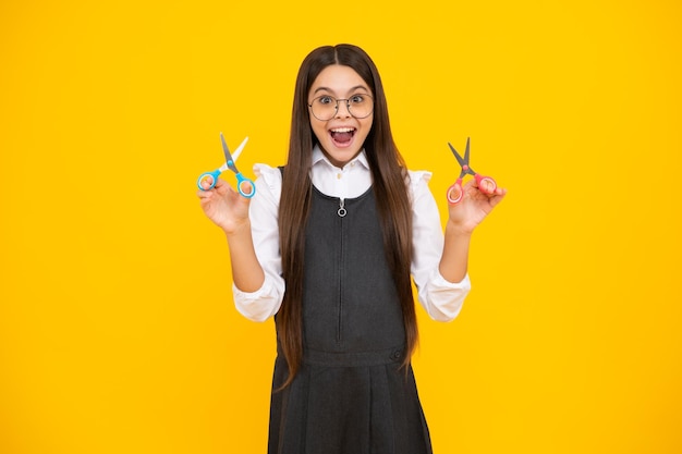 Ragazza della scuola dell'adolescente con le forbici isolate su sfondo giallo Strumenti fai da te per le arti e i mestieri della creatività del bambino