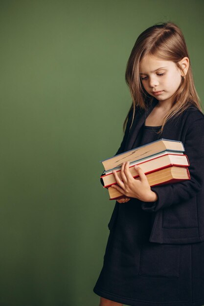 Ragazza della scuola in libri della tenuta dell'uniforme