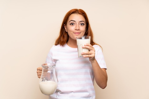 Ragazza della testarossa dell'adolescente che tiene un bicchiere di latte