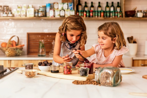 Ragazza delle sorelline che prepara i biscotti di cottura. Concetto di chef infantile.