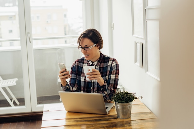 Ragazza dello studente che controlla i media sociali, leggendo i commenti sul suo nuovo post