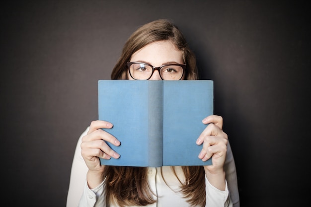 Ragazza dello studente che si nasconde dietro un libro