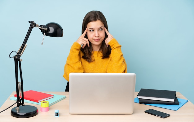 Ragazza dello studente che studia nella sua casa sull'azzurro che ha dubbi e pensare