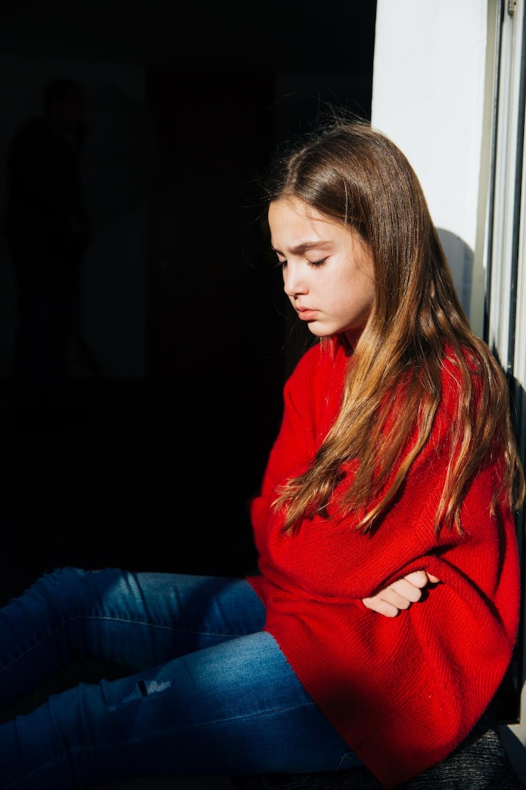 Foto ragazza depressa seduta sul davanzale della finestra