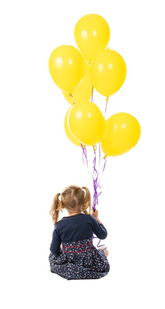 Ragazza di 3 anni che tiene un gruppo di palloncini gialli.