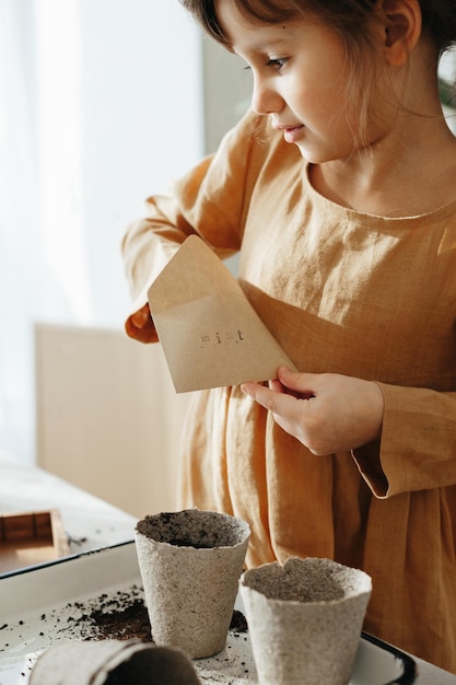 Ragazza di 6 anni che pianta erbe a casa