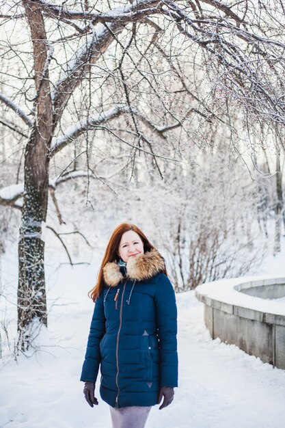 Ragazza di aspetto europeo in una passeggiata nella foresta invernale, parco, inverno e neve, salute, abiti invernali, giacca