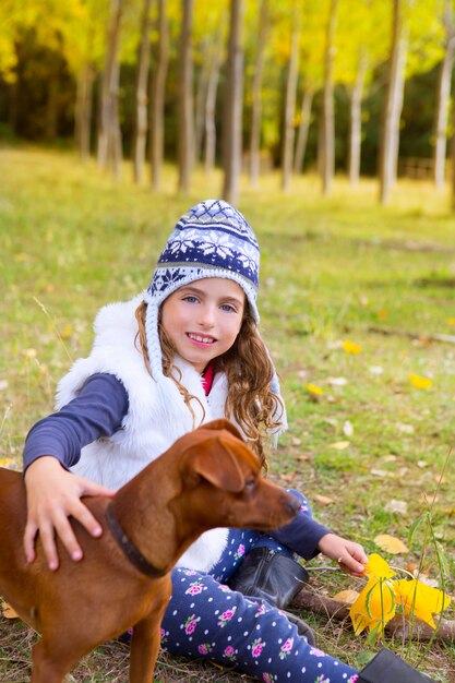 Ragazza di autunno nella foresta dell&#39;albero di pioppo che gioca con il cane