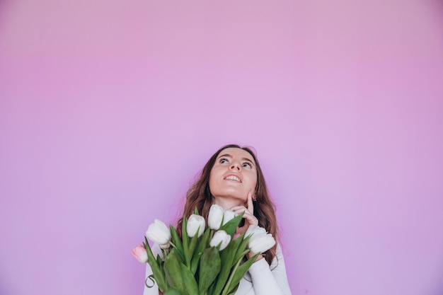 Ragazza di bellezza che tiene i tulipani della primavera Mazzo del fiore e sorridente. San Valentino. Festa della mamma.