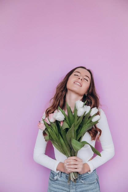 Ragazza di bellezza che tiene i tulipani della primavera Mazzo del fiore e sorridente. San Valentino. Festa della mamma.