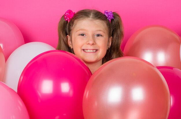 Ragazza di bellezza con palloncini colorati sorridenti su sfondo rosa.