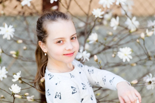 Ragazza di bellezza sul fiore floreale in primavera Bambino di bellezza con un aspetto fresco e capelli lunghi