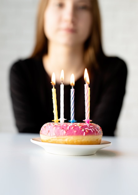 Ragazza di compleanno dell'adolescente che soffia candele sulla ciambella