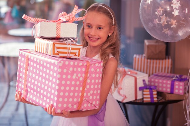 Ragazza di compleanno emozionante che sorride mentre tiene i suoi grandi regali