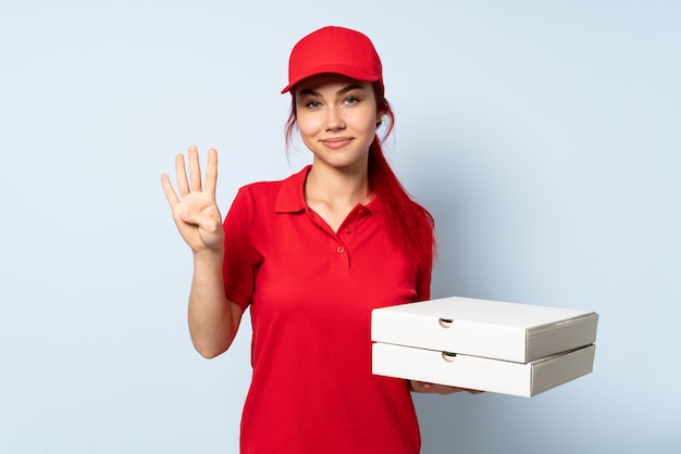 Ragazza di consegna della pizza che giudica felice una pizza sopra la parete isolata e che conta quattro con le dita