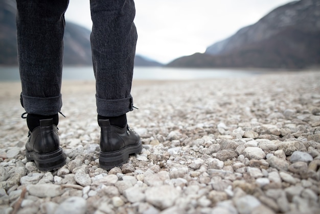 Ragazza di escursionismo in natura. Inquadratura dal basso di scarpe sportive generiche e gambe sulla strada sterrata di ciottoli