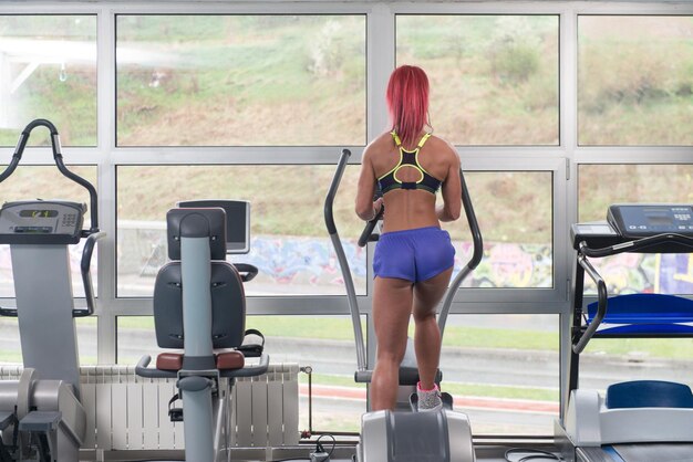 Ragazza di forma fisica che si esercita sul tapis roulant Moonwalker in un moderno centro fitness