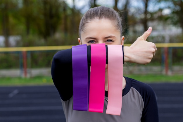 Ragazza di forma fisica che tiene tre allungamenti di gomma fitness