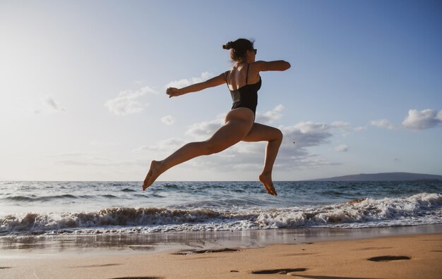 Ragazza di forma fisica sana della siluetta corrente della donna che pareggia alla spiaggia