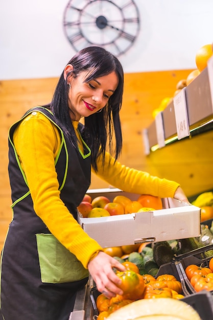 Ragazza di frutta bruna che lavora per ordinare frutti in uno stabilimento di fruttivendolo