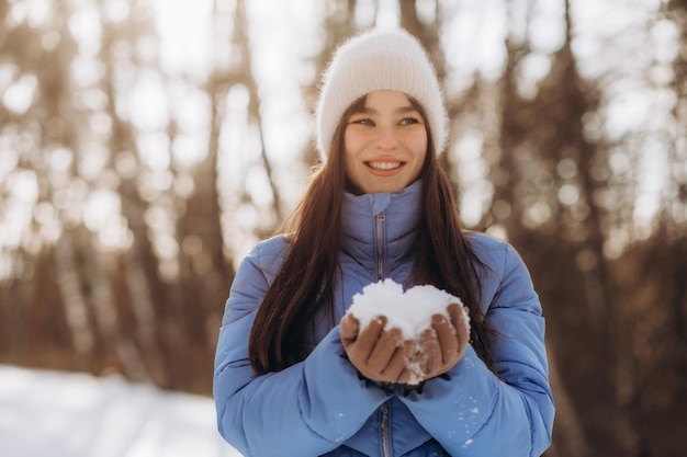 Ragazza di inverno che soffia neve Bellezza gioiosa ragazza modello adolescente divertirsi a winter park