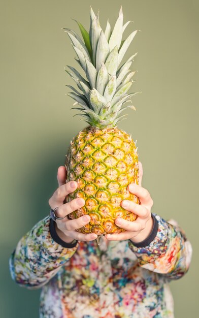 Ragazza di moda che tiene l'ananas davanti al viso