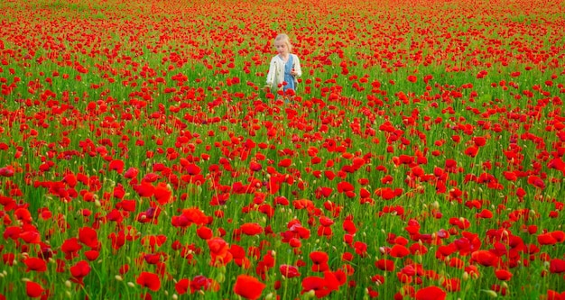 Ragazza di primavera Bella bambina indossa abiti casual nel campo dei fiori di papavero Sfondo di fiori di primavera