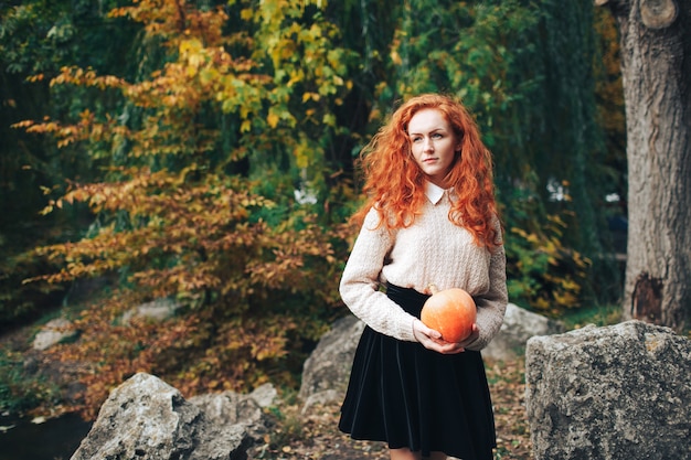 ragazza di redhead azienda zucca in autunno parco