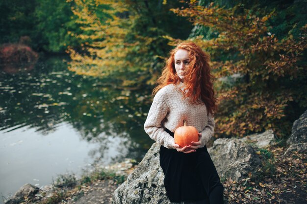 ragazza di redhead azienda zucca in autunno parco