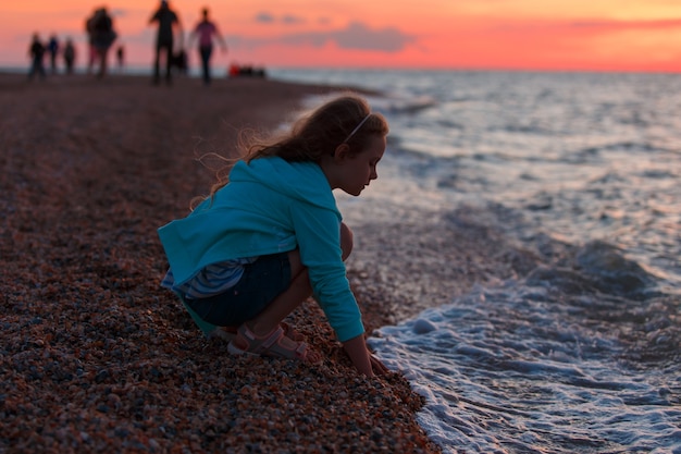 Ragazza di sette anni sulla spiaggia all'ora del tramonto.