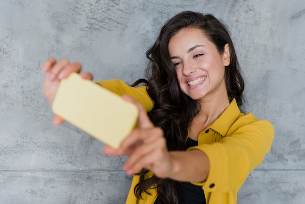 Ragazza di smiley del colpo medio che prende un selfie