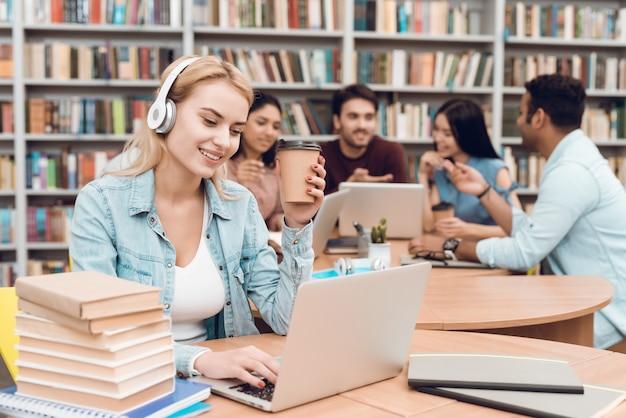 Ragazza di sorriso che lavora al computer portatile con le cuffie.