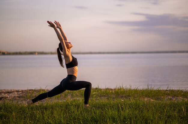 Ragazza di sport che fa yoga sulla spiaggia