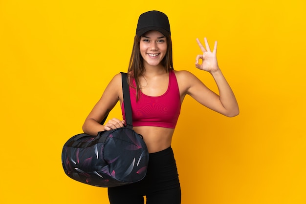 Ragazza di sport dell'adolescente con la borsa di sport che mostra segno giusto con le dita