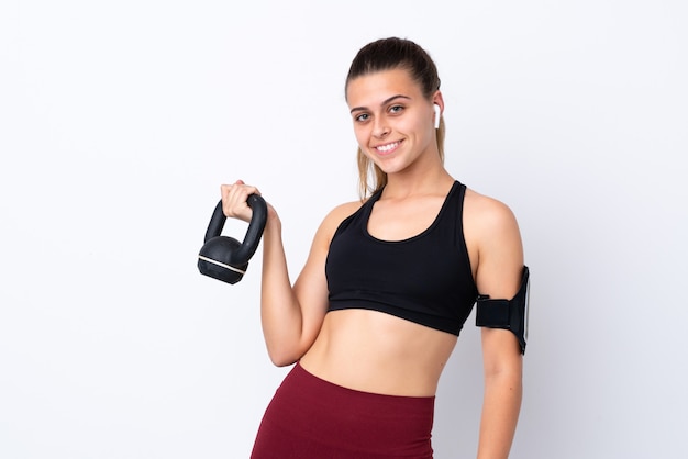 Ragazza di sport dell'adolescente sopra sollevamento pesi di fabbricazione bianco isolato con kettlebell