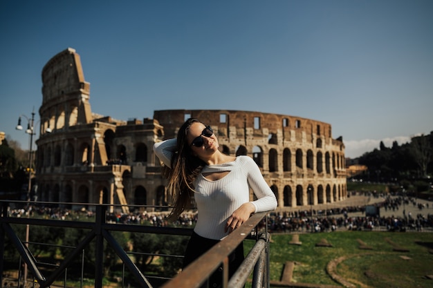 Ragazza di viaggio sorridente e in posa contro il Colosseo romano.