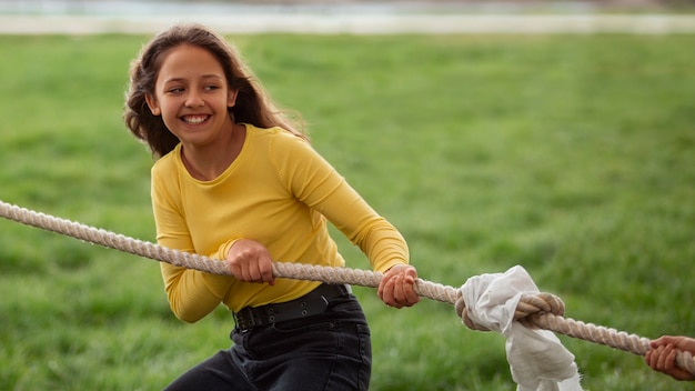 Ragazza di vista frontale che gioca al tiro alla fune nel parco