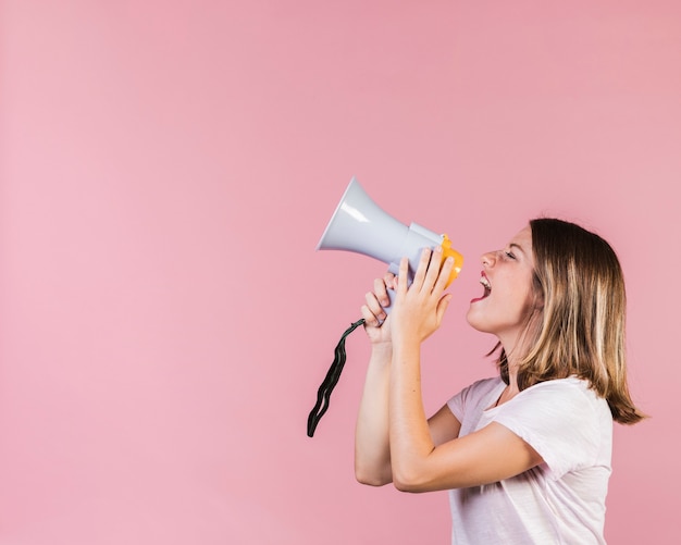 Ragazza di vista laterale che grida su un megafono