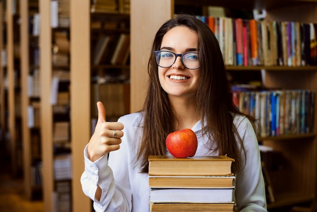 Ragazza diligente dello studente che mostra i pollici su