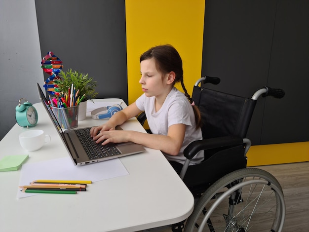 Ragazza disabile in sedia a rotelle con il computer portatile a casa