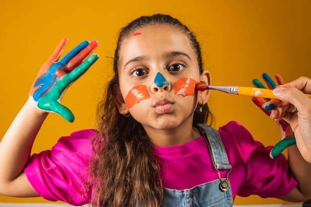 Ragazza divertente con le mani dipinte con vernice colorata. Ragazza dipinta con vernice e pennello