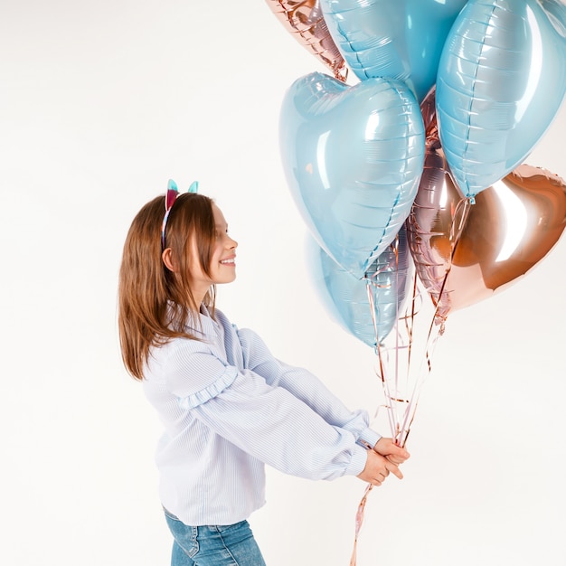 Ragazza divertente con le orecchie di gatti che tengono i palloni. Compleanno di concetto